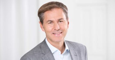 Halb-Porträt von Prof. Martin Weigel, Vorstand der GLC AG, lächelnd im grauen Sakko mit hellblauem Hemd