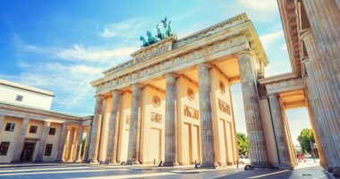 Berliner Tor unter baluem Himmle an einem Frühlingstag mit grünen Bäumen im Hintergrund